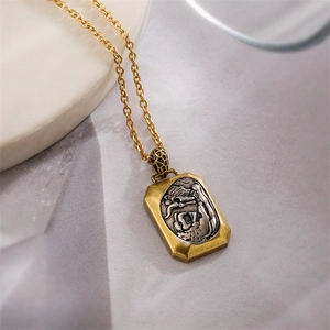 Détail d'une chaîne dorée avec pendentif rectangulaire antique et relief de dragon gravé
