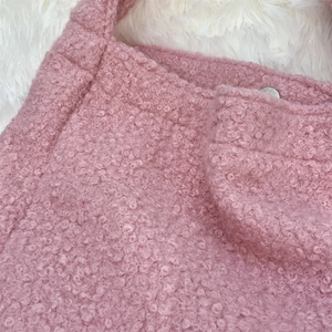Detail of pink teddy fleece tote bag fabric with curly texture and silver rivet closure