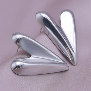 Macro shot of silver heart studs with polished mirror finish on purple satin background