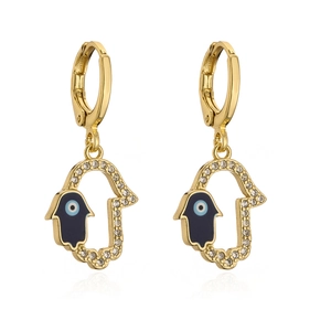 Macro detail of 18K gold-plated Hamsa hand earrings with blue evil eye and zircon studs