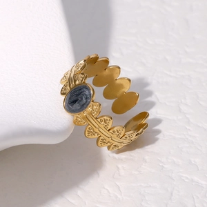 Macro detail of adjustable gold leaf ring featuring a dark oval gemstone inlay