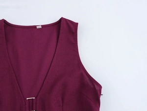 Détail d'une robe bordeaux à col en V profond et boucle métallique à la taille