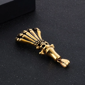 Macro detail of golden skeleton claw holding a skull pendant on dark background