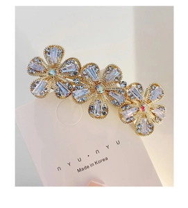 Detail of flower hair clip with rectangular crystals and rhinestones on a gold base