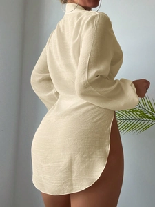 Dettaglio del copricostume beige a maniche lunghe con tessuto a trama e spacchi laterali