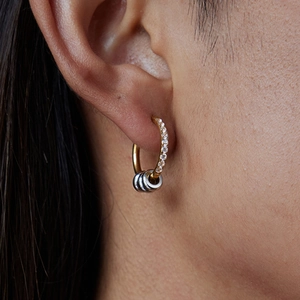 Close-up of mixed metal hoop earrings with gold and silver rings and white diamond detail