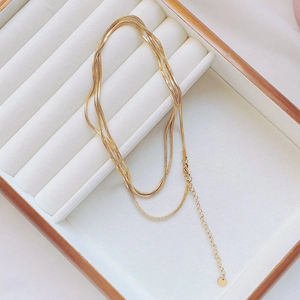 Close-up of gold layered snake chain necklace with adjustable link on white display