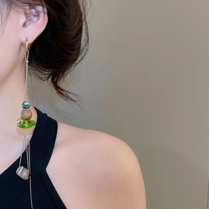 Detail of vintage tassel earrings with green beads and striped agate stone on model