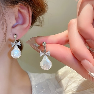 Close-up of bow knot earrings with baroque pearls and sparkling zircons on model