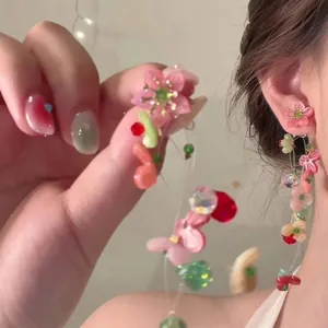 Detail of pink acrylic flower earrings with colorful bead fringe on a model