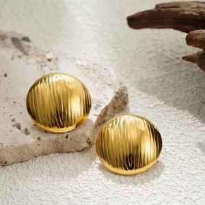 Detailed close-up of gold geometric striped earrings on a decorative stone