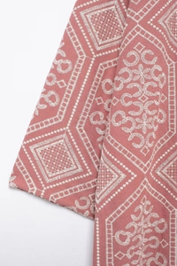 Close-up of pink long cardigan fabric with intricate white geometric diamond embroidery