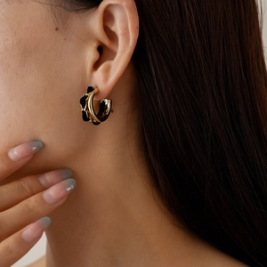 Boucles d'oreilles créoles dorées en C avec tissu noir sur le profil du mannequin