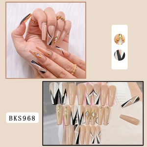 Detail of long coffin press-on nails in nude with black geometric lines and gold rhinestones