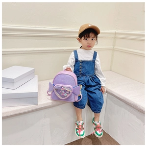 Detail of purple sequin toddler backpack with heart window and wings on a model