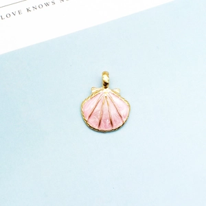 Detailaufnahme eines rosa Emaille-Muschel-Anhängers mit goldener Metallkante