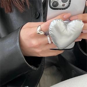 Minimalist silver heart ring and matching puffer phone grip shown on a model