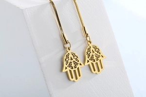 Vue détaillée de la main de Hamsa dorée avec motifs ajourés et chaîne serpent lisse