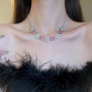 Detail of flower necklace with square pink gemstone worn by model in black feather top