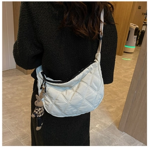 Rear view of a white quilted dumpling bag with a small bunny charm and wide strap