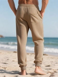 Detail of men's beige waffle knit joggers showing back view on a sunny beach background