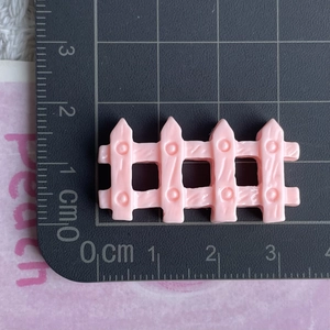 Macro detail of a pink resin fence miniature accessory on a measuring scale mat