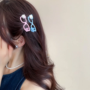 Close-up of cute pink and blue cat glasses hair clips on wavy brown hair styles