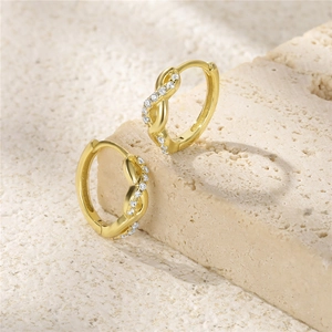 Macro detail of gold-plated twisted hoop earrings with sparkling cubic zirconia inlay