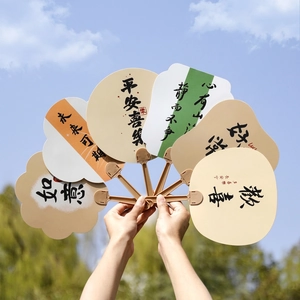 Calligraphy handheld fans in various shapes held against a natural blue sky background