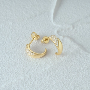 Close-up of gold hoop earrings featuring sparkling pavé-set white cubic zirconia stones