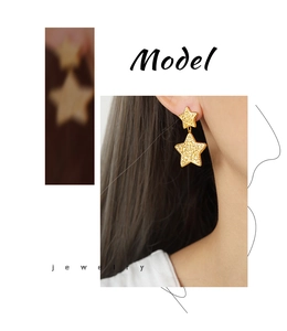Gros plan de boucles d'oreilles pendantes double étoile dorées à texture sur un mannequin