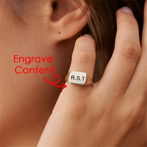 Detail shot of customized gold square ring with RST engraving on model finger
