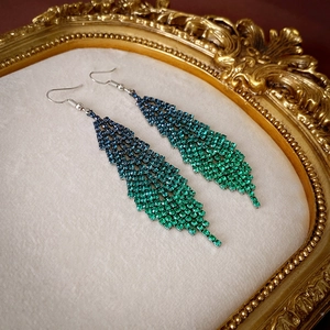 Detailed macro view of long feather fringe earrings with blue and green rhinestone gradient