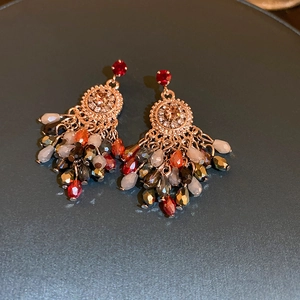 Close-up of rose gold crystal earrings with colorful beaded tassels and rhinestone details