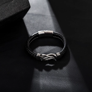 Close-up of dual-tone leather braid and silver magnetic knot clasp on men's bracelet