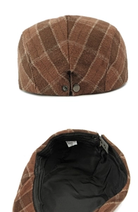 Detailed view of brown plaid flat cap featuring a metal buckle and interior wash label
