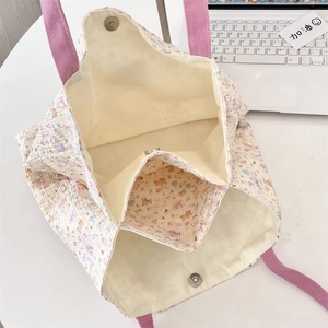 Detail view of canvas tote bag featuring magnetic closure and internal storage pocket