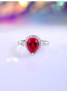 Detail of pear-cut ruby silver ring with halo diamonds and twisted pavé band style