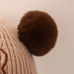 Detail of winter knit hat featuring a soft faux fur pom-pom and thick knit texture