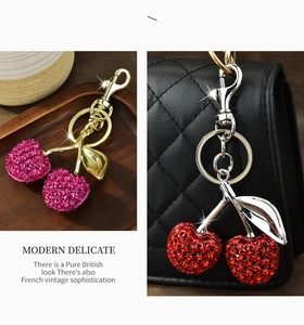 Macro shot of sparkling crystal cherry keychains in pink and red on a luxury handbag