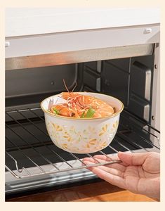 Japanese ceramic bowl with yellow floral patterns being placed into a hot oven