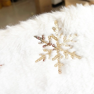 Detail of soft white faux fur Christmas tree skirt with golden sequin snowflake patterns