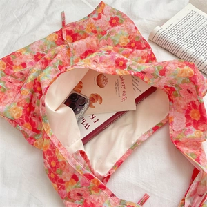 Top view of pink floral canvas tote bag showing spacious interior with books and phone