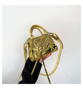Detailed close-up of golden metallic faux leather handbag with rivets and tassels