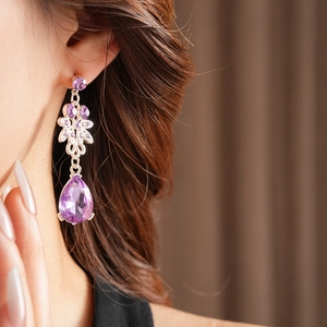 Detail view of vintage purple zircon flower drop earrings on model with silver-tone finish