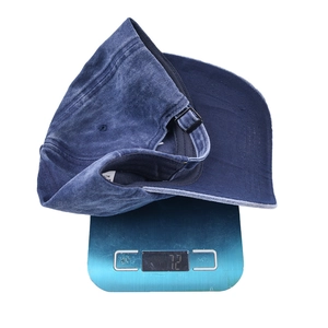 Detail shot of a navy washed vintage cotton baseball cap weighing 72g on a scale