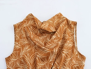 Close-up of the elegant draped neck and silky brown palm leaf print on the sleeveless dress