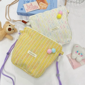 Detail of tweed crossbody phone bags with colorful embroidery and pom-pom decorations