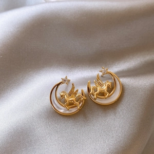 Detailed view of moon and unicorn earrings with zircon stars on silk fabric