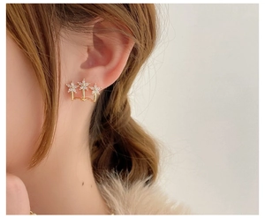Close-up of golden floral stud earrings with inlaid sparkling cubic zirconia on ear